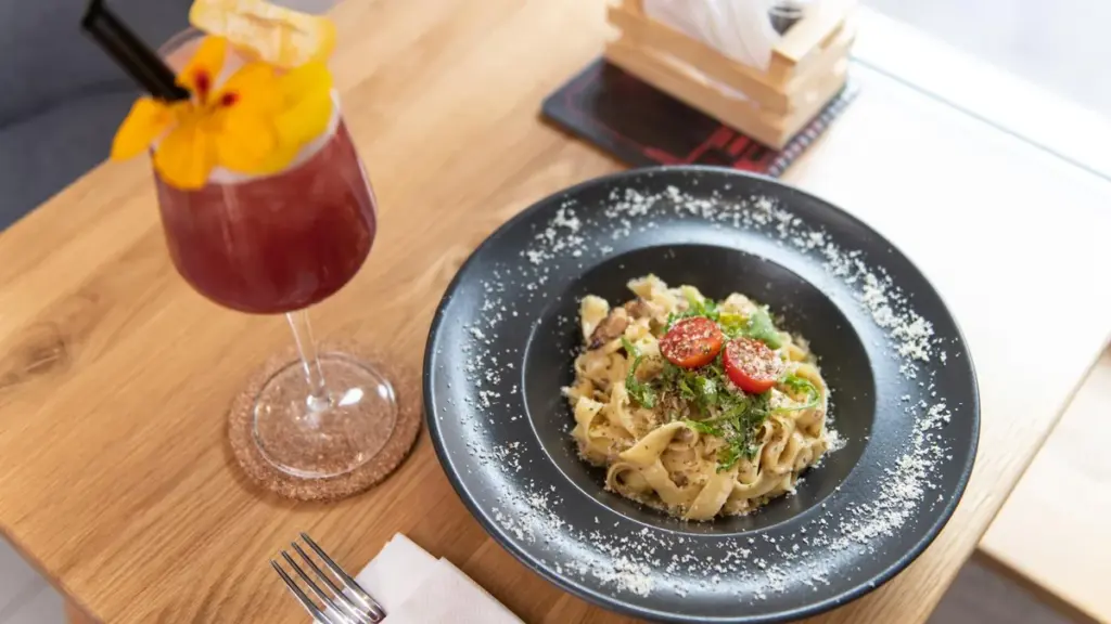 Prato de massa com tomate e bebida sobre mesa de madeira em restaurante